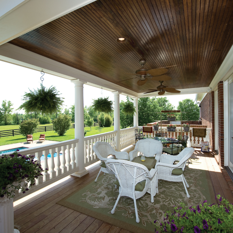 Covered porch with white columns overlooking pool and backyard