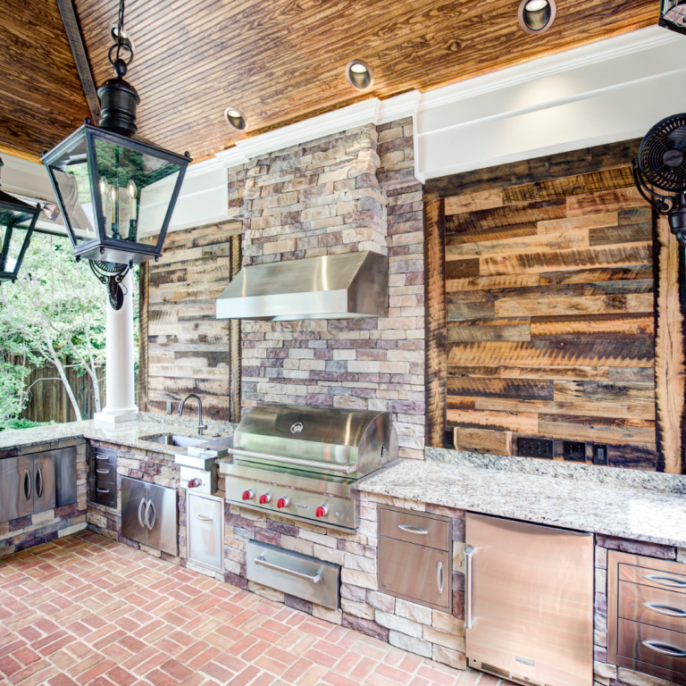 Outdoor kitchen with stainless steel appliances, a stone countertop bar, and seating in a backyard in Lexington.